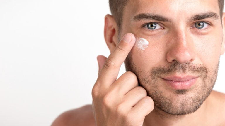 Homme aplliquant de la crem anti cerne homme